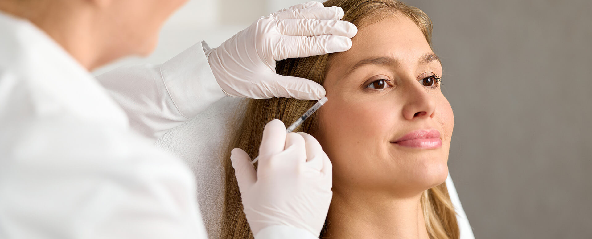 Ärztin setzt einer Patientin eine Botox-Injektion in die Stirnpartie