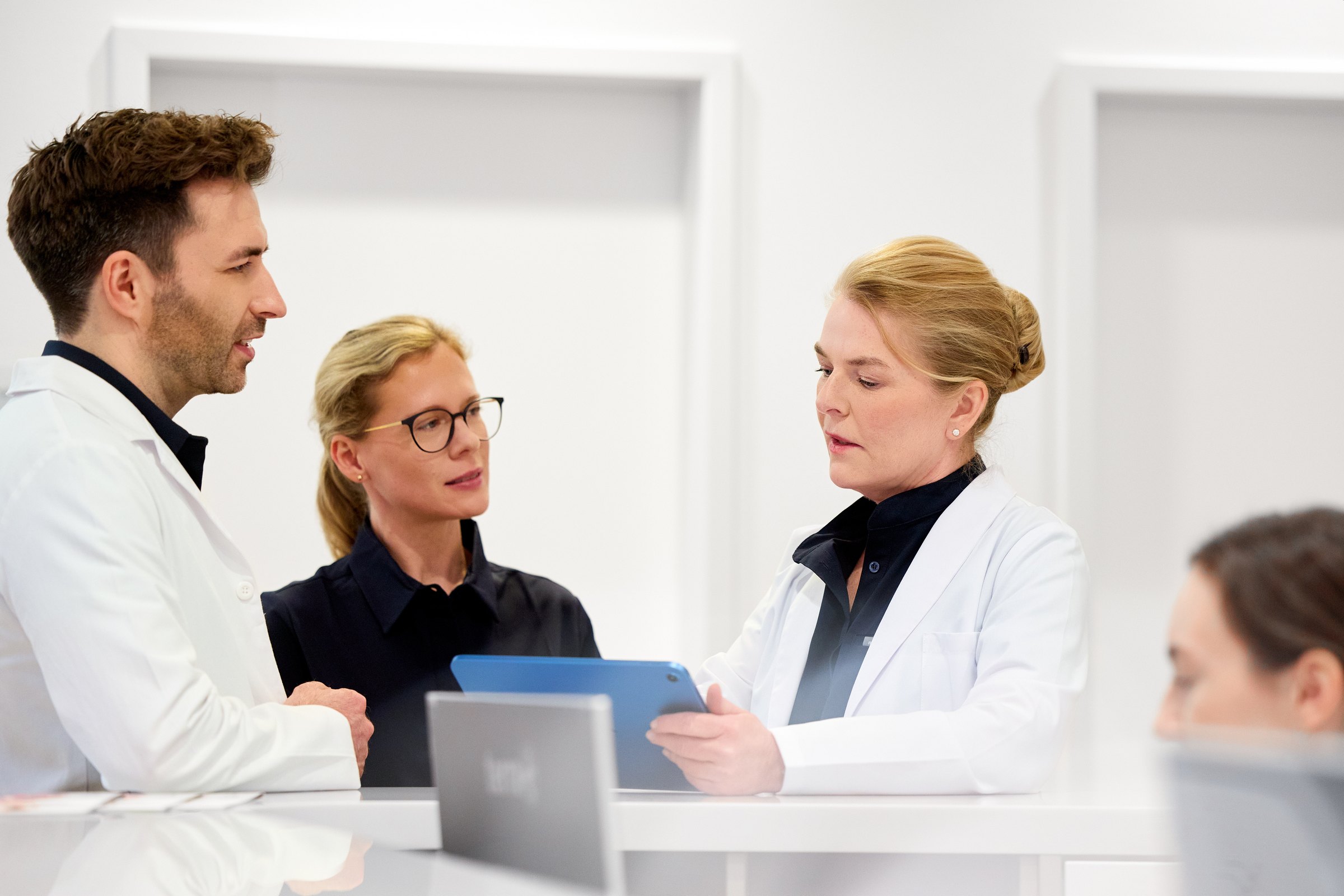 Drei Mitglieder des Teams der Hamburg Dermatologie stimmen sich am Tablet ab