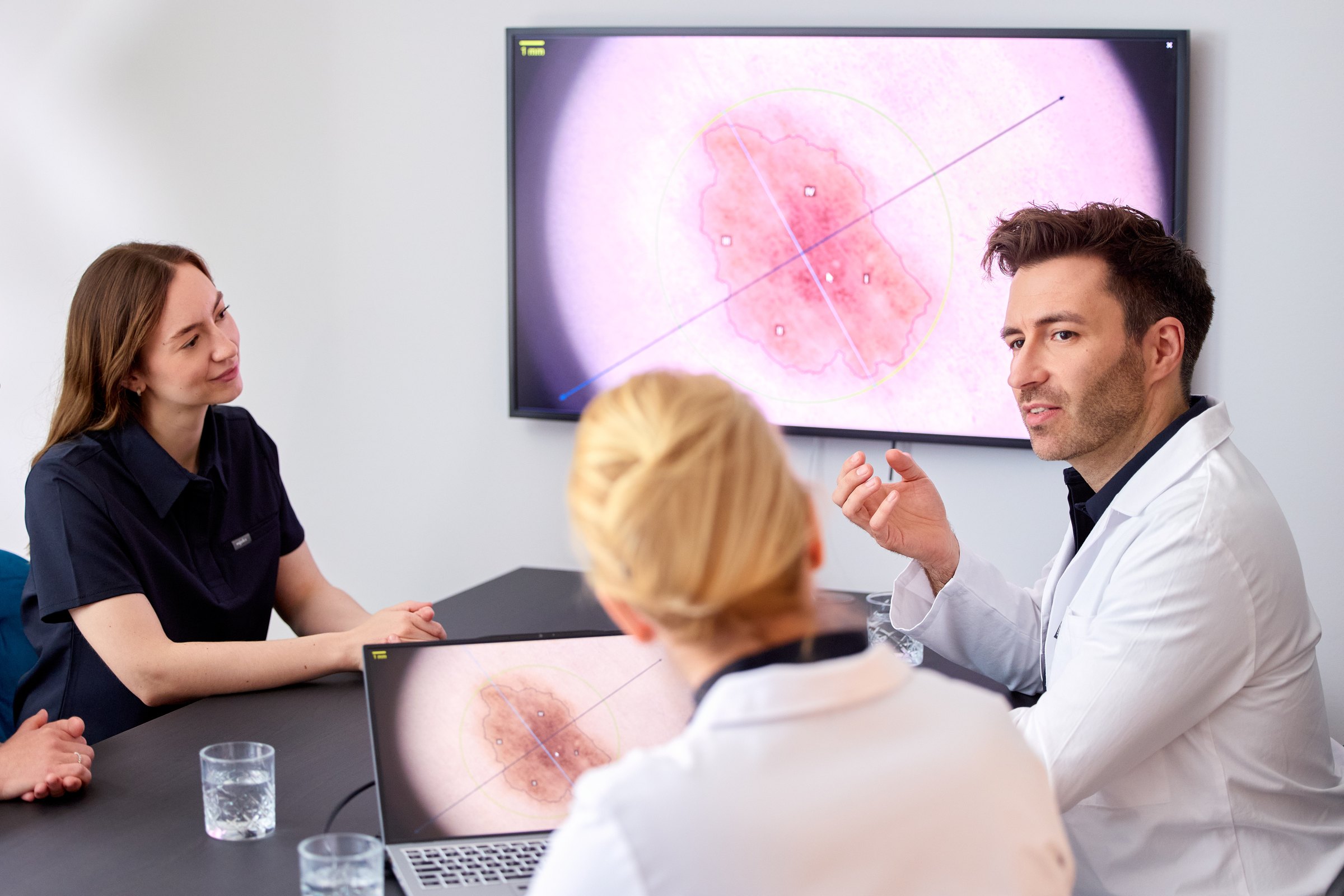 Befundbesprechung im Team, im Hintergrund ein vergrößertes Hautbild